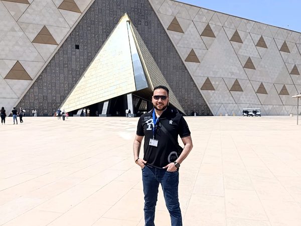 Michael Sabry in front of the pyramid-shaped entrance of the Grand Egyptian Museum