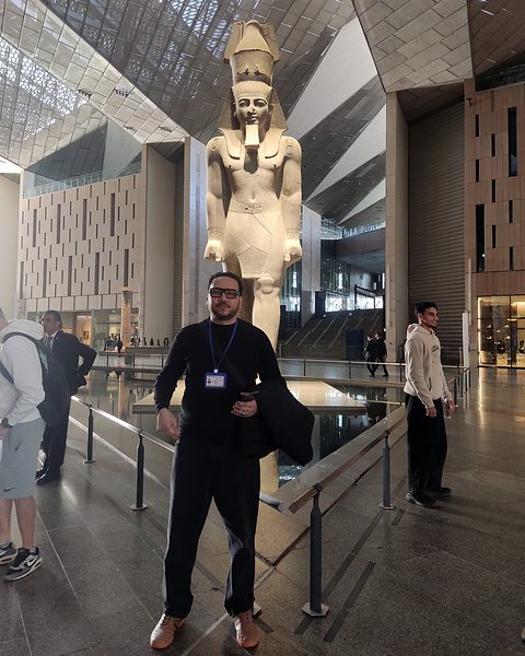 Michael Sabry in front of the colossal statue of Ramesses II in the Grand Hall of the Grand Egyptian Museum
